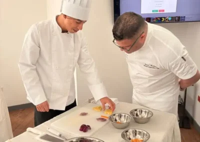 Instructor chef guiando a estudiante durante práctica de gastronomía en Forever Culinary